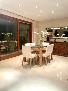 奥尔比亚Double A Luxury Apartment的一间带木桌和白色椅子的用餐室