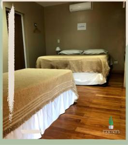 圣萨尔瓦多德朱Caminos Hostal的铺有木地板的客房内的两张床