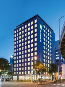 名古屋ibis Styles Nagoya的一座高大的建筑,旁边有一个标志