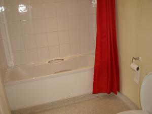 彼索普斯托福愉快酿酒者自由宾馆的浴室设有白色浴缸和红色的淋浴帘