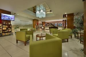 贝龙里塔瓦贝龙大酒店的一间设有绿色椅子、桌子和钢琴的餐厅