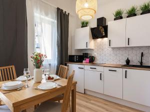 科沃布热格VacationClub - Olymp Apartment 502A的厨房配有木桌和白色橱柜。