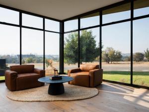 比勒陀利亚Askara Haus的客厅配有两把椅子、一张桌子和大窗户