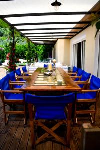 圣帕拉斯凯维Serenity Luxury Villa, Skiathos的甲板上配有一张带蓝色椅子的大型木桌
