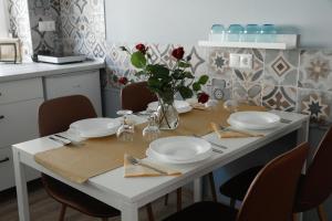 科马罗姆Apartman 3的一张带板子的白色桌子和一个红色玫瑰花瓶