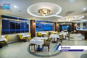 埃利特温泉Zir Dream Thermal & Spa Hotel的餐厅设有白色的桌椅和窗户。
