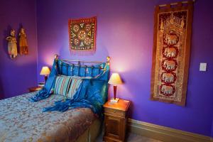纳皮尔Sea Breeze B & B的一间卧室设有紫色墙壁、一张床和两盏灯。