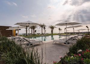 韦拉克鲁斯Best Western Plus Riviera Veracruz的一个带遮阳伞和椅子的游泳池以及一个游泳池
