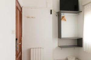毕尔巴鄂阿里亚斯酒店的带冰箱的厨房和墙上的电视