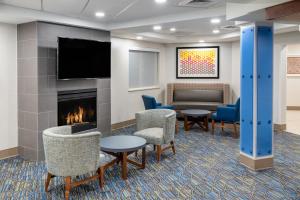 科罗拉多斯普林斯Holiday Inn Express & Suites Colorado Springs-Airport, an IHG Hotel的大堂设有壁炉、椅子和沙发。