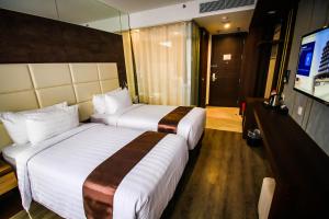 名古屋Asialink Hotel Batam by Prasanthi的酒店客房设有两张床和一台平面电视。