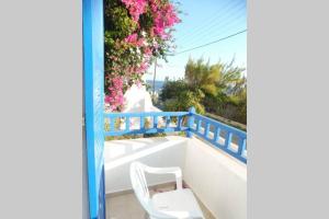 阿波罗3 min from the beach-White&blue house in Apollon的白色椅子,坐在带鲜花的阳台