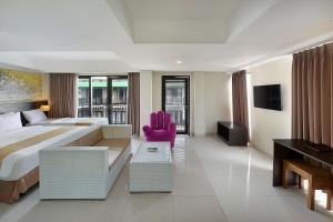 勒吉安Rofa Kuta Hotel - CHSE Certified的酒店客房设有一张大床和一张粉红色的椅子。