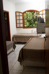 贝洛奥里藏特Pousada Lagoa的客房设有两张床、一台电视和一扇窗户。