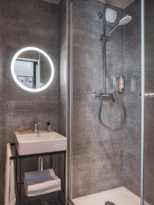 巴黎Hôtel Piapia的带淋浴、盥洗盆和镜子的浴室
