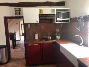 拉纳肯Hômage的一间带红色橱柜和微波炉的厨房