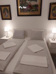 布达佩斯Melinda Apartman 2的一张带两张桌子和两盏灯的白色床