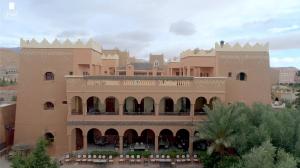 廷吉尔Hotel Kasbah Lamrani的一座大型棕褐色建筑,前面设有阳台