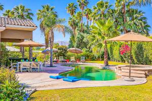 兰乔米拉日Indulgent Escape In Rancho Mirage的一个带遮阳伞和桌椅的游泳池