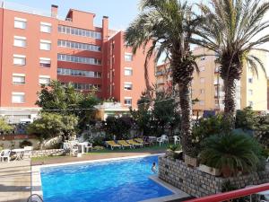 卡里拉Apartaments Mar Blau Calella的棕榈树建筑前的游泳池