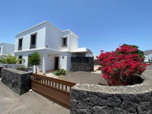 普拉亚布兰卡Varadero Nauplius的白色的房子,有栅栏和红色的鲜花