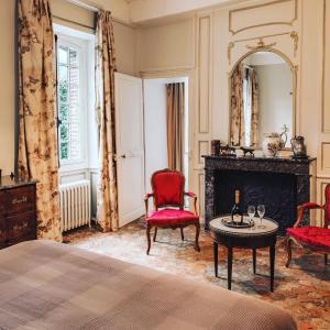 VillotranAu vieux Château的一间卧室设有壁炉、红色椅子和镜子