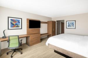 凤凰城Holiday Inn Express & Suites - Phoenix - Airport North, an IHG Hotel的配有一张床铺的书桌和一台电视机的酒店客房