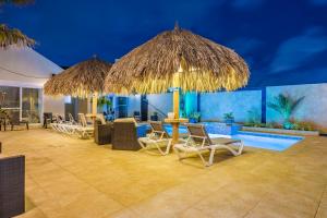 棕榈滩金色别墅式酒店的一个带椅子和遮阳伞的庭院和一个游泳池
