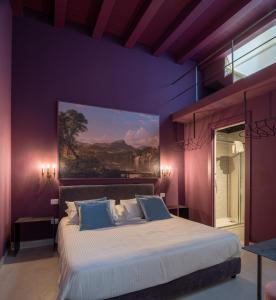 锡拉库扎ORTIGIAdreamrooms 14的卧室配有一张大床,墙上挂有绘画作品
