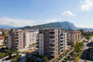 安纳马斯Nehô Suites Porte de Genève的一座公寓楼,位于一座城市中,以群山为背景