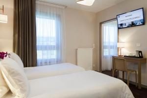 安纳马斯Nehô Suites Porte de Genève的酒店客房设有两张床、一张书桌和一个窗户。