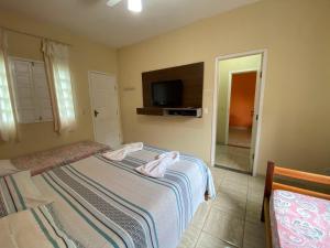 伊塔乌纳斯Pousada Nossa Casa的一间卧室配有两张床和一台平面电视