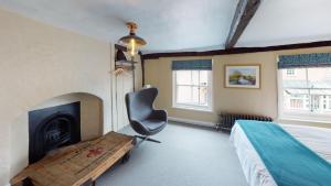 戴德姆The Marlborough Dedham的一间卧室配有一张床、一把椅子和一个壁炉