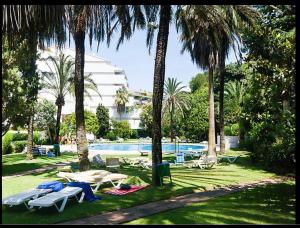 马贝拉Jardines del Mar ,Casa Apolonia的一个带椅子和桌子的游泳池,并种植了棕榈树