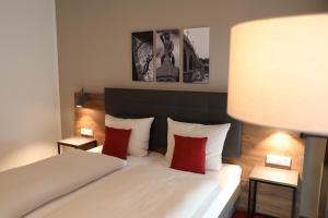 雷根斯堡Hotel INCLUDiO的卧室配有带红色枕头的白色床
