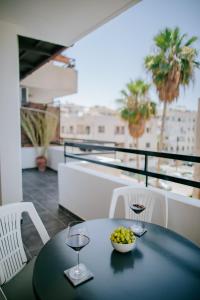拉纳卡Lazaros Centre Apartment的阳台上的桌子上放着一碗葡萄和酒杯