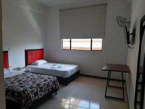 OcañaHotel Majestic的一间卧室设有两张床、一张桌子和一个窗口