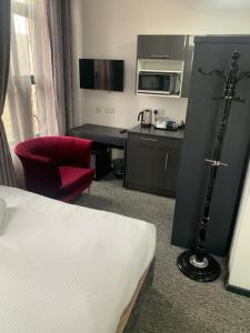 诺丁汉诺丁汉特里维尔斯摄政酒店的酒店客房,配有一张床和一张红色椅子