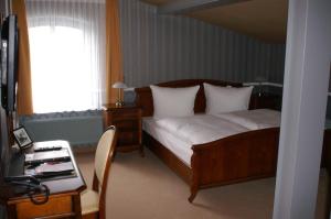 MeyenburgEisenbahnromantik Hotel的一间卧室配有一张床、一张书桌和一个窗户。