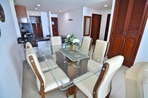 卡塔赫纳Torres del Lago Apartamentos的一间设有玻璃桌和白色椅子的用餐室