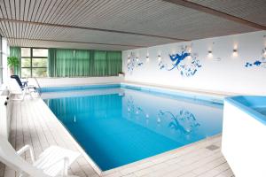 维林根维林森林酒店的游泳池(铺有蓝色和白色瓷砖地板)和游泳池