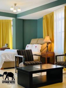 姆万扎LEYSHOF HOTEL的客厅配有床、沙发和桌子