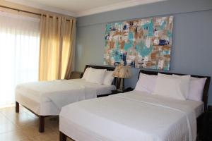 Bortianor博约海滩度假酒店的卧室内的两张床,墙上有绘画作品