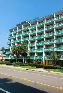默特尔比奇Quail Inn and Suites - Myrtle Beach的一条街道前方棕榈树的大型公寓楼