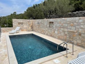 尼亚卢卡Holiday Home Tranquility的一座带石墙和石头的游泳池