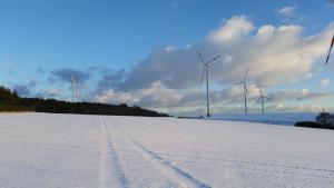 Ober KostenzKehrmühle的底部有风力涡轮机的雪覆盖场