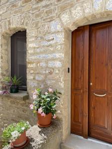 皮耶特拉佩尔托萨Petra Holiday Home的石头建筑的入口,种植了盆栽植物,设有木门