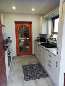 布什米尔斯Craig Cottage Self-catering的厨房配有白色橱柜、水槽和门