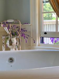 哈利法克斯The Pebble Bed and Breakfast的白色浴室水槽,带窗户和紫色的鲜花
