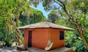 因巴塞Pousada Aldeia Banzaê的一座橙色的小房子,里面挂着吊床